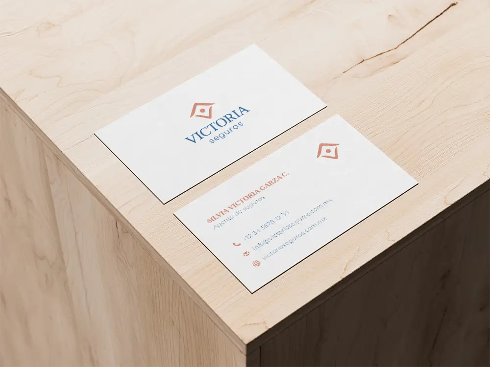 Secondary vertical logo variation for Victoria Seguros, an insurance agent, displayed on her business card, ensuring consistent and professional branding across touchpoints.